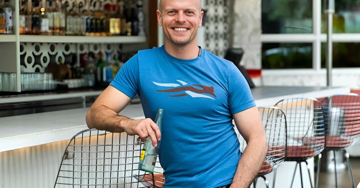 A person in a blue t-shirt standing in front of a bar.