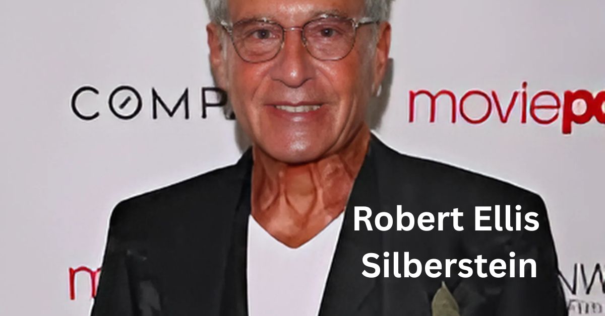 A person in a black jacket and white shirt standing on a red carpet
