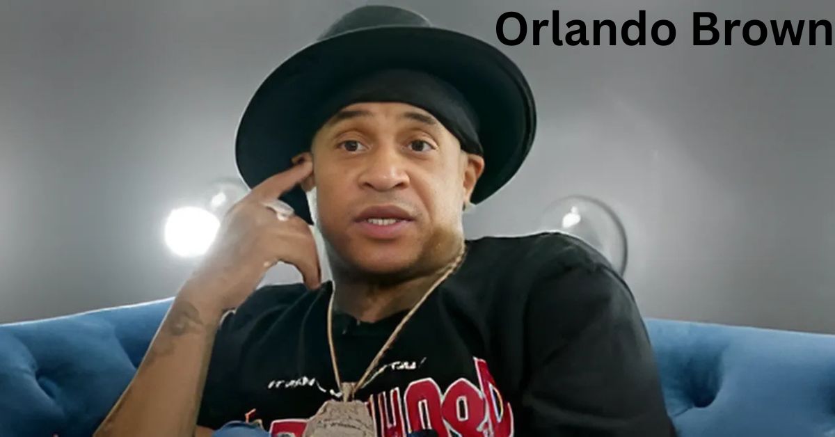 A person in a hat sitting on a couch talking on the phone.