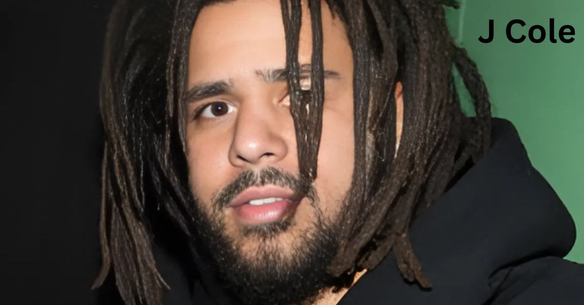 A person with dreadlocks standing in front of a green wall