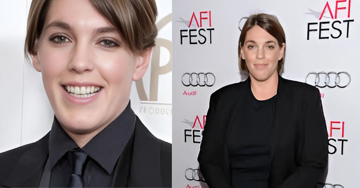 A person in a black suit standing on a red carpet
